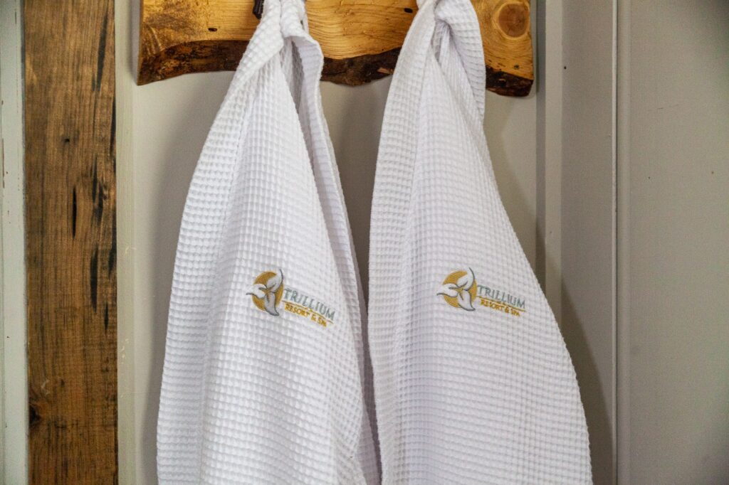 White waffle-weave towels with Trillium Resort logo on rustic hook showcasing spa hotel amenities Muskoka Port Sydney Huntsville
