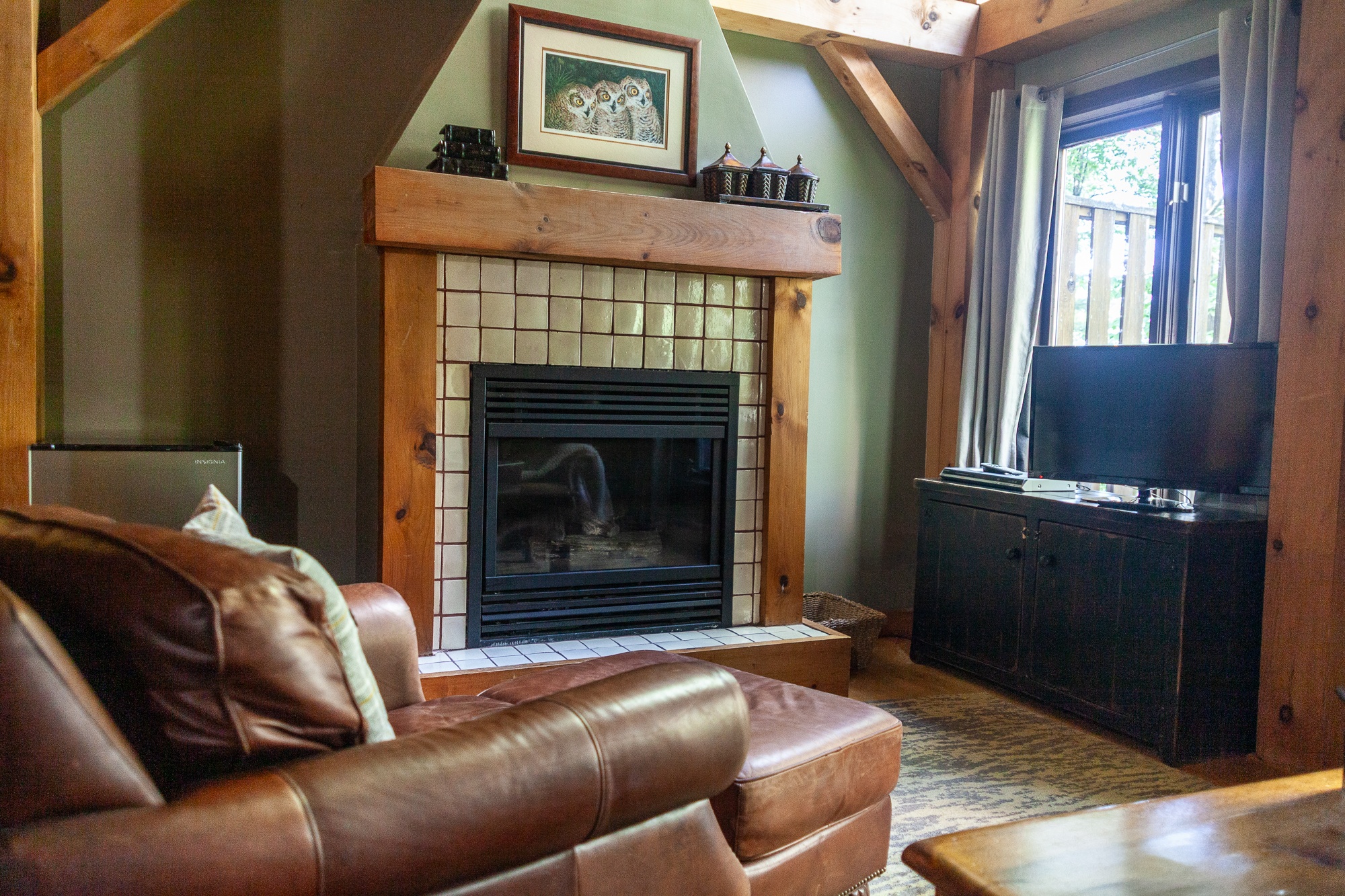 Rustic chalet living room with exposed beams stone fireplace and leather seating at Trillium Resort and Spa Muskoka Huntsville