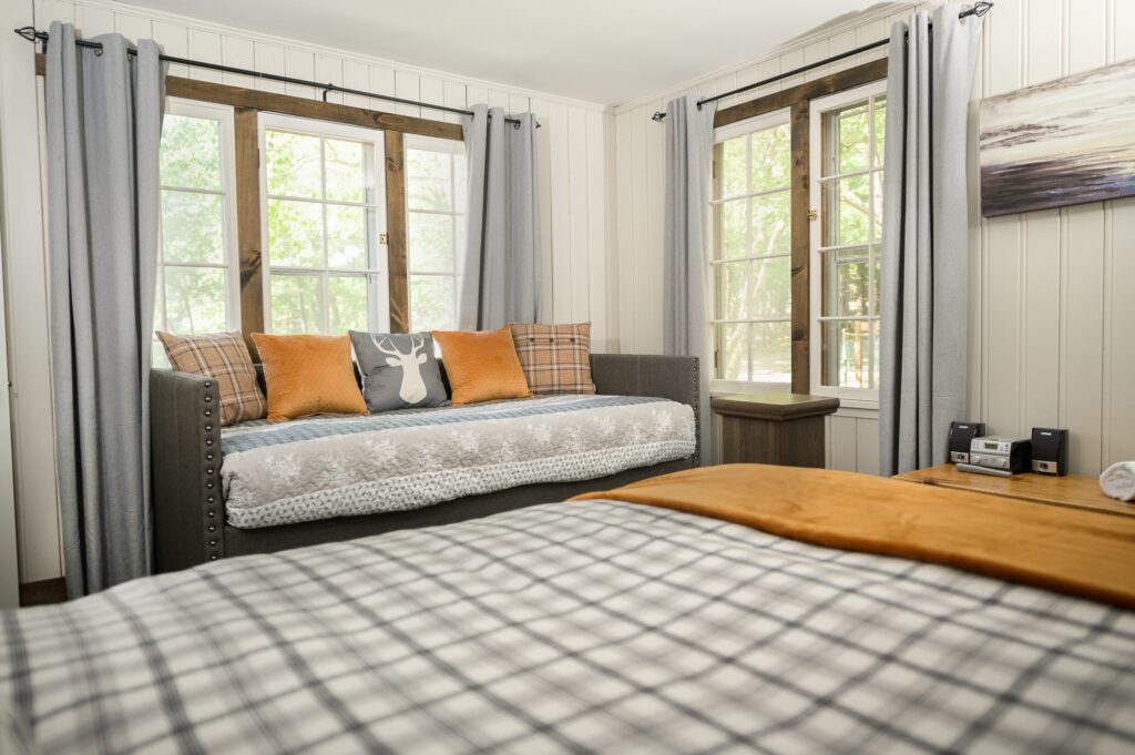 Bright guest bedroom with upholstered daybed and forest views in Falling Water cottage at Trillium Resort and Spa Muskoka Port Sydney