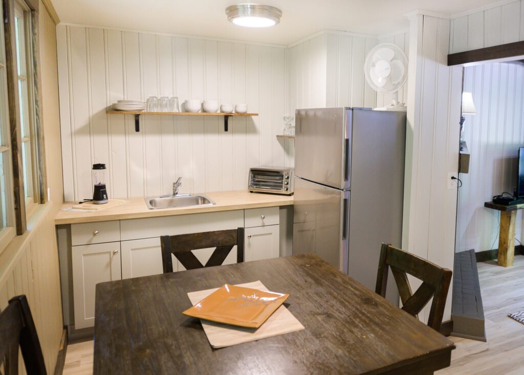 Compact kitchenette with stainless steel fridge and open shelving in Falling Water cottage at Trillium Resort and Spa Muskoka Huntsville
