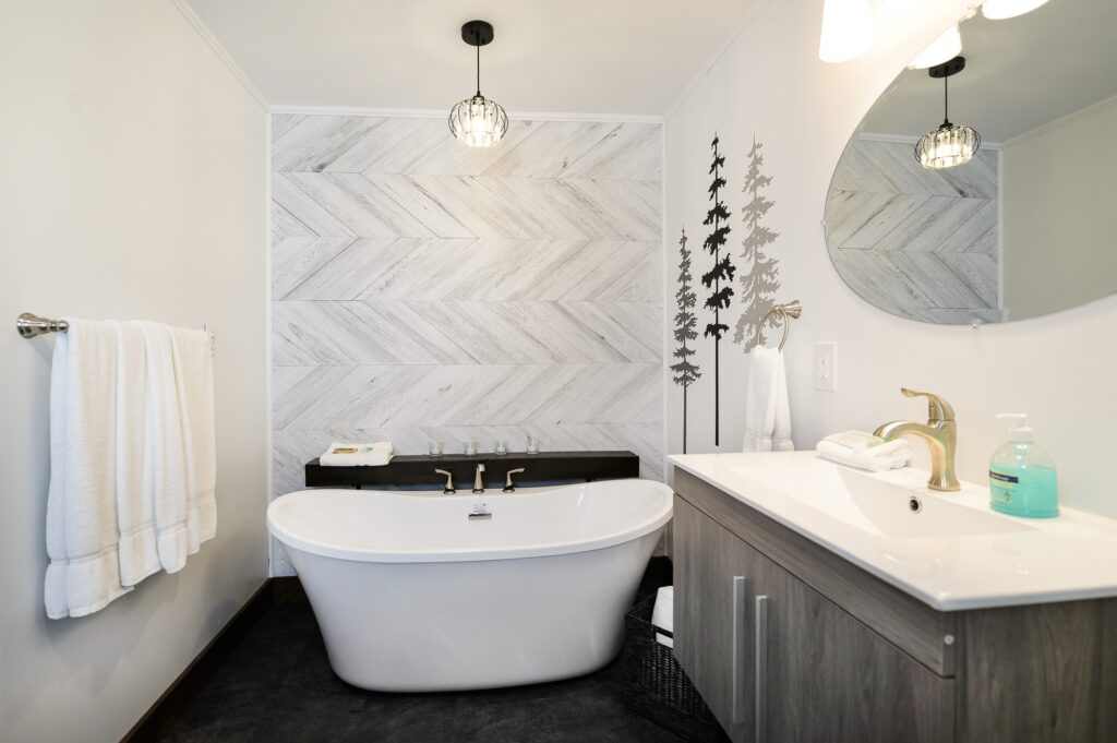 Luxury freestanding soaking tub with herringbone marble accent wall in Falling Water cottage ensuite at Trillium Resort and Spa Muskoka