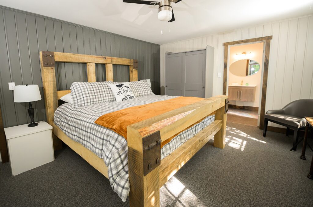 Rustic master bedroom with handcrafted wood bed and natural sunlight in Falling Water cottage at Trillium Resort and Spa Muskoka Huntsville