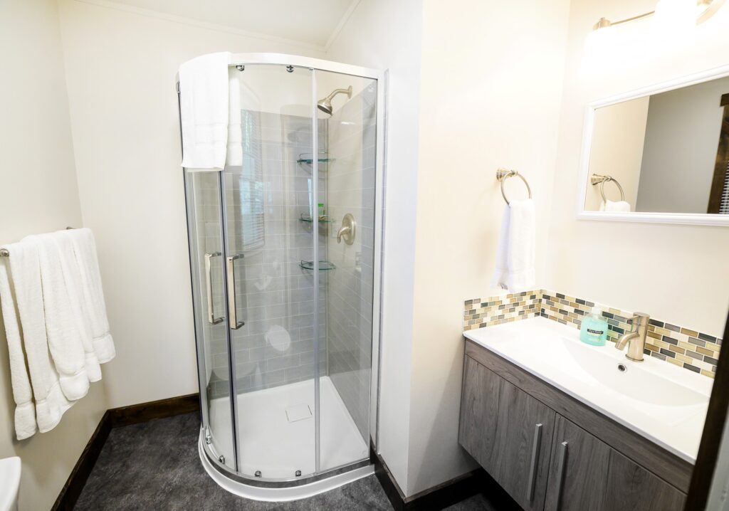 Contemporary second bathroom with curved glass shower and mosaic tile in Rushing Water Suite at Trillium Resort and Spa Muskoka