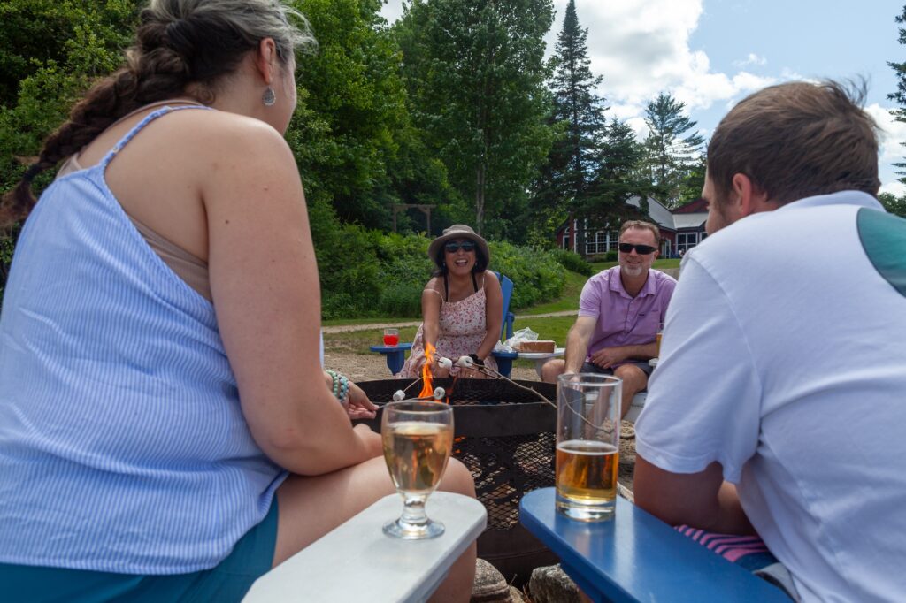 Friends gathered around outdoor fire pit enjoying summer drinks at Trillium Resort and Spa Muskoka Huntsville Port Sydney