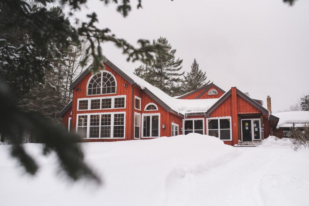 Trillium Resort and Spa red lodge post-and-beam under winter snow with forest Muskoka Huntsville Port Sydney
