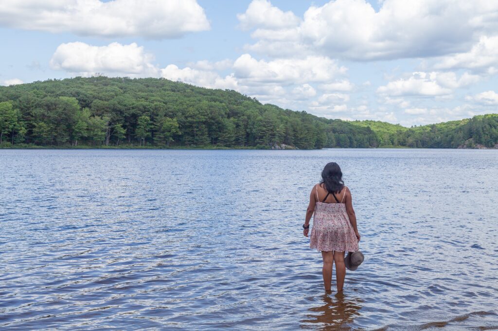 Woman wading into clear blue Muskoka lake in summer at Trillium Resort and Spa beach Port Sydney Huntsville