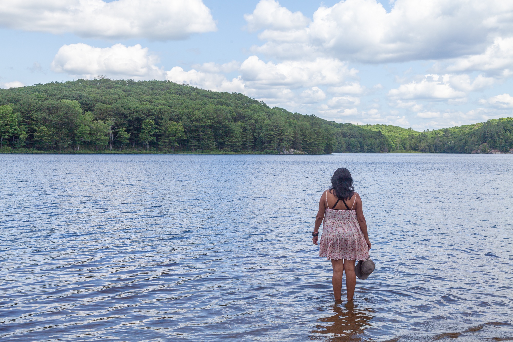 Woman wading into clear blue Muskoka lake in summer at Trillium Resort and Spa beach Port Sydney Huntsville