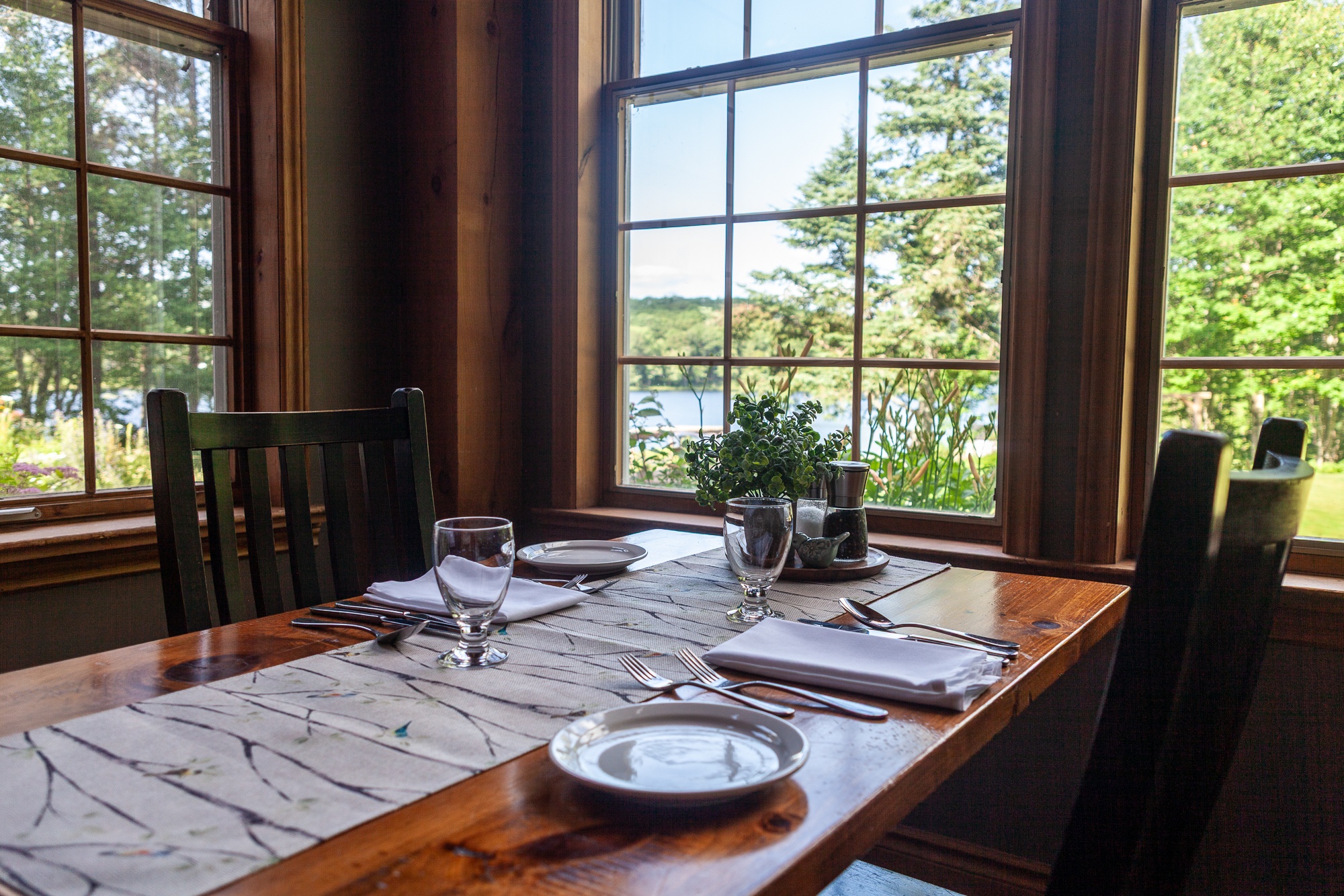Elegantly set dining table with panoramic lake views through large windows at Trillium Resort and Spa restaurant Muskoka Huntsville