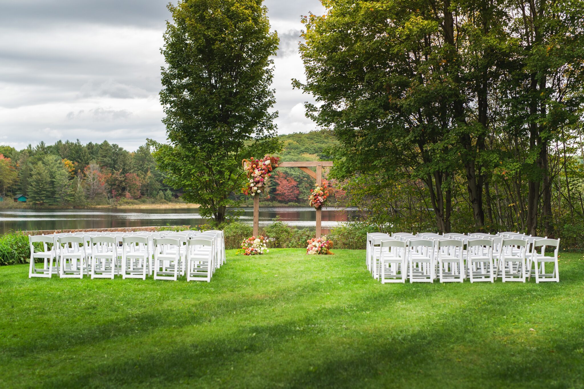 Lakeside outdoor wedding ceremony setup with white chairs and floral arrangements at Trillium Resort and Spa Muskoka Huntsville Port Sydney