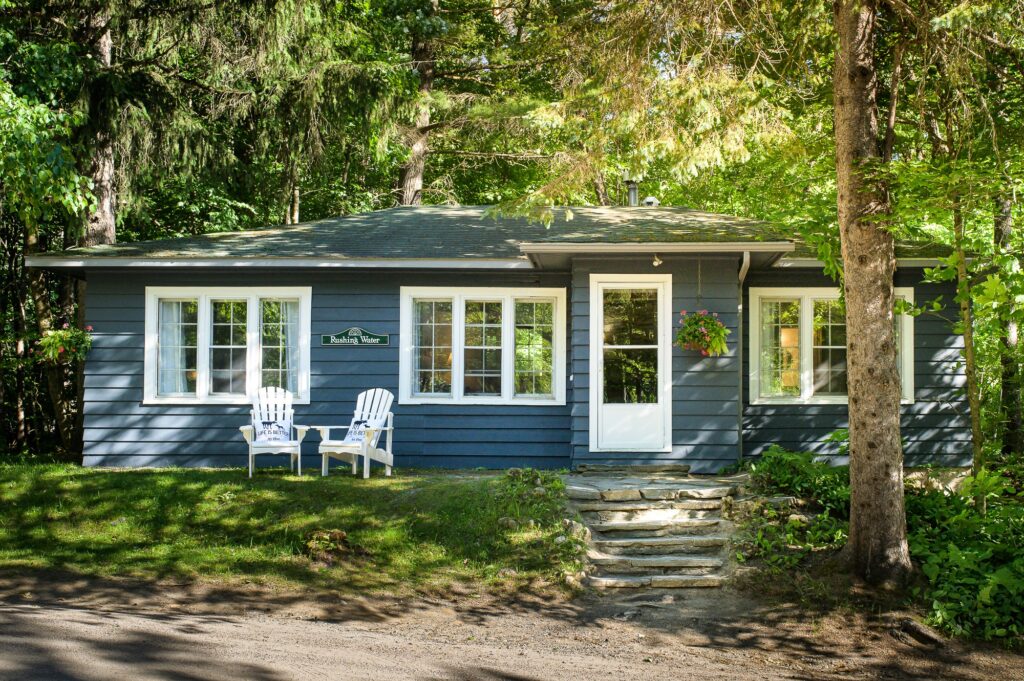 Rushing Water suite cottage nestled among mature tree forest with Muskoka chairs at Trillium Resort and Spa Muskoka Huntsville