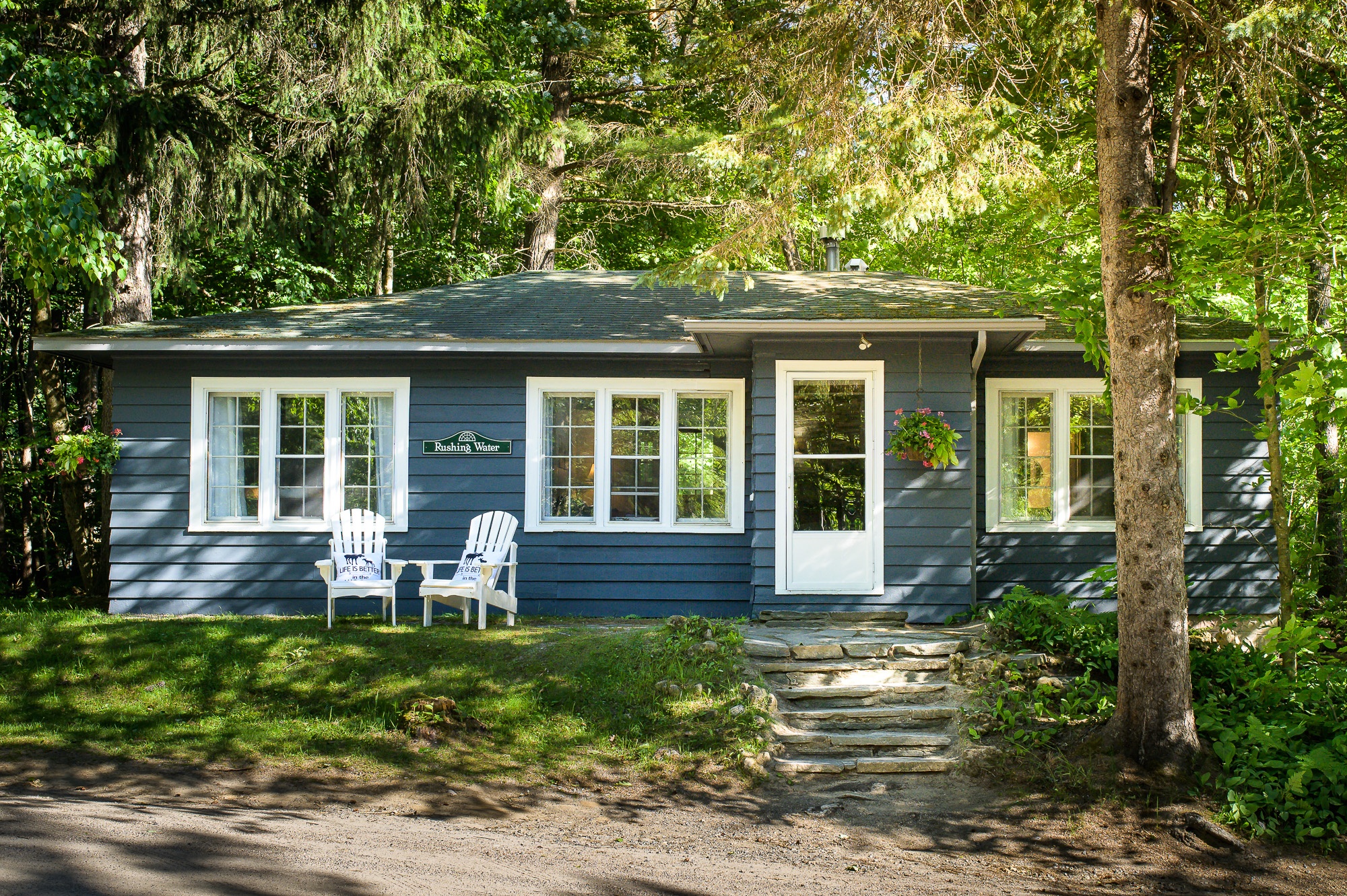 Rushing Water suite cottage nestled among mature tree forest with Muskoka chairs at Trillium Resort and Spa Muskoka Huntsville