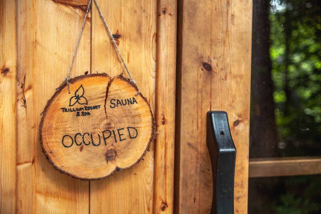 Rustic wooden occupied sign on Muskoka sauna at Trillium Resort with Trillium Resort and Spa branding Huntsville